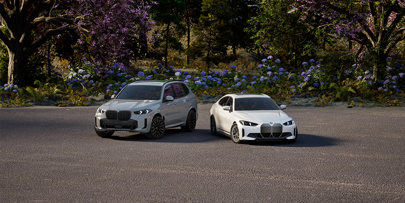 Vehículos eléctricos BMW aparcados en un paisaje primaveral.