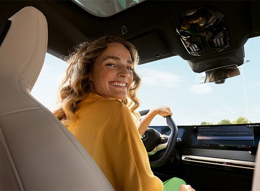Mujer sentada en el asiento del conductor de un BMW, con la pantalla visible.