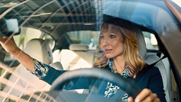 Una mujer ajusta su espejo retrovisor desde el asiento del conductor